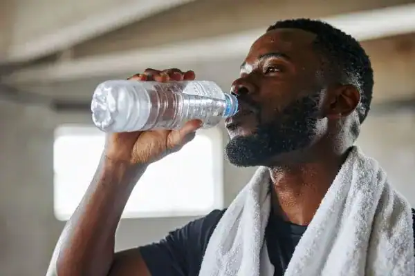Image of man drinking water to improve hydration Wales after work out.